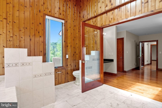 bathroom with wood walls, toilet, and hardwood / wood-style flooring