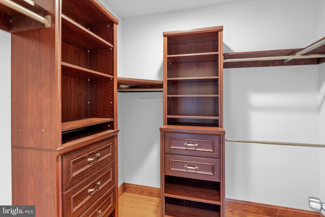 walk in closet with light hardwood / wood-style flooring