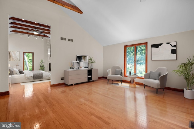 living area featuring a healthy amount of sunlight, beamed ceiling, and light hardwood / wood-style flooring