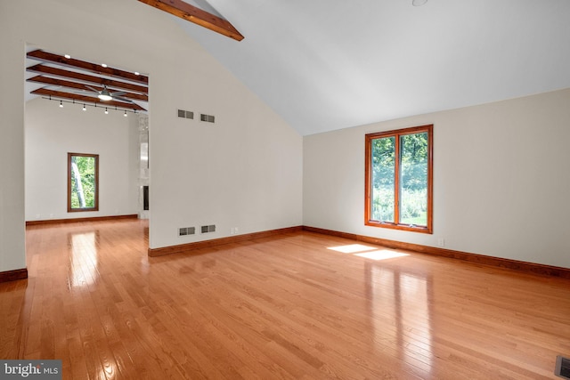 unfurnished living room with ceiling fan, light wood-type flooring, beam ceiling, and high vaulted ceiling