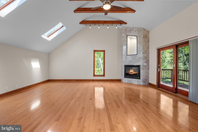 unfurnished living room with high vaulted ceiling, light wood-type flooring, beamed ceiling, and a large fireplace