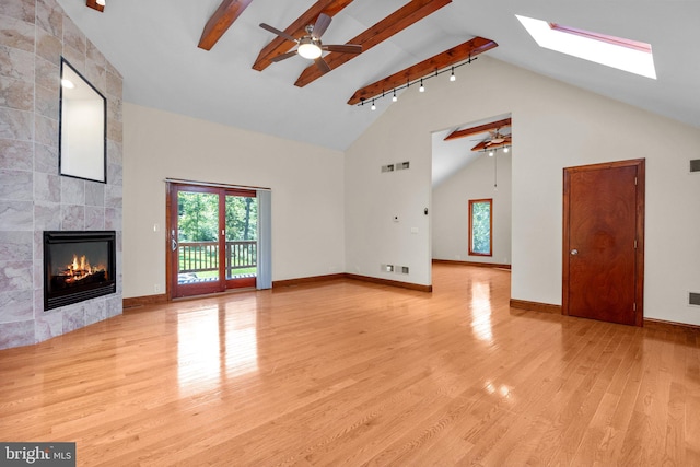 unfurnished living room with high vaulted ceiling, a fireplace, beamed ceiling, light wood-type flooring, and ceiling fan