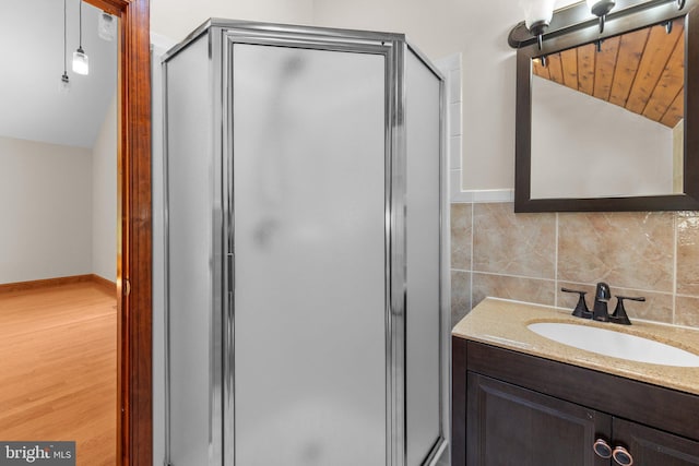 bathroom with hardwood / wood-style flooring, an enclosed shower, lofted ceiling, decorative backsplash, and vanity