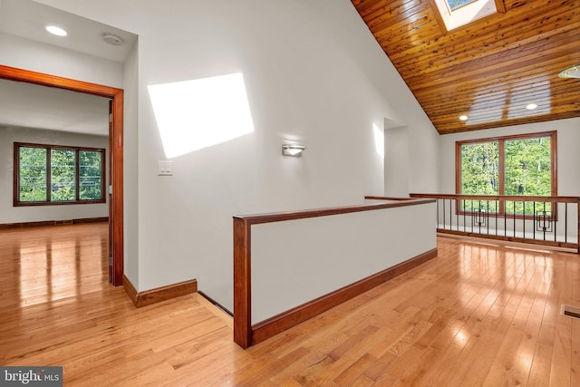 hall with vaulted ceiling with skylight, wooden ceiling, and light wood-type flooring