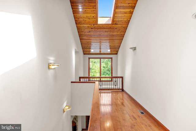 hallway with light hardwood / wood-style flooring, lofted ceiling with skylight, and wooden ceiling