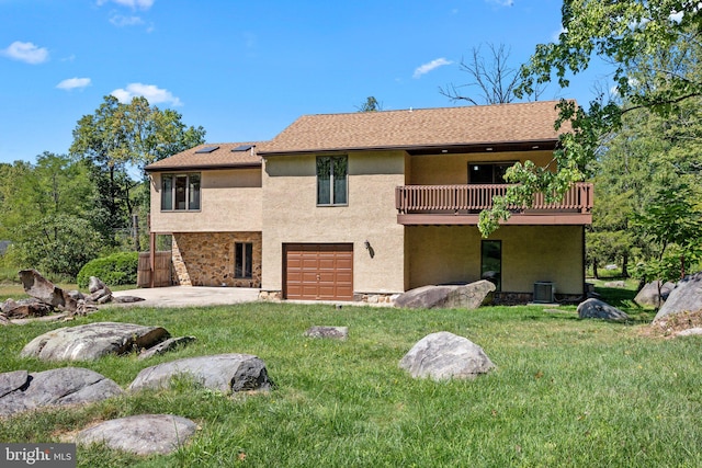 rear view of property featuring a yard, a garage, and a patio area