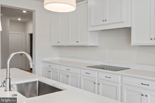 kitchen featuring black electric cooktop, white cabinetry, and sink