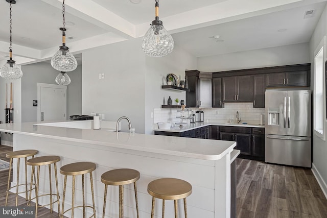 kitchen featuring stainless steel fridge, hanging light fixtures, backsplash, dark hardwood / wood-style flooring, and sink