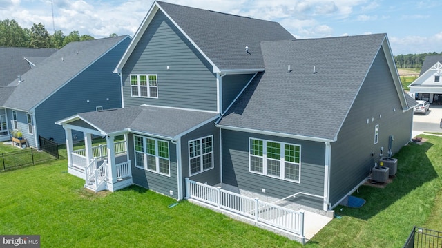 rear view of house featuring cooling unit and a yard