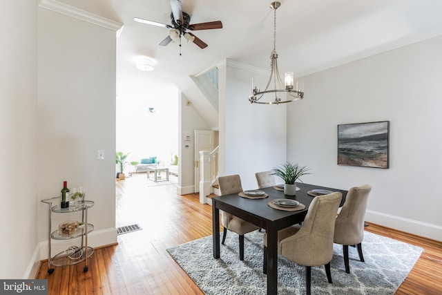 dining room with crown molding, light wood-type flooring, and ceiling fan with notable chandelier