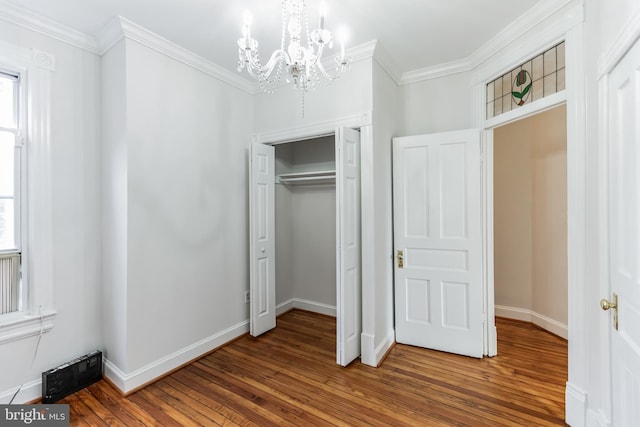 unfurnished bedroom with a notable chandelier, wood-type flooring, ornamental molding, and a closet