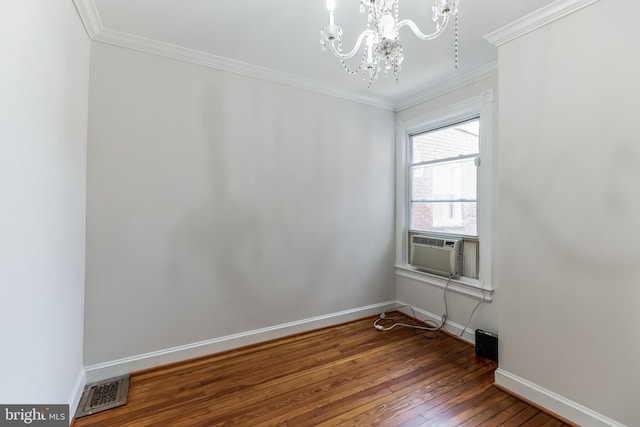 unfurnished room featuring wood-type flooring, cooling unit, ornamental molding, and an inviting chandelier