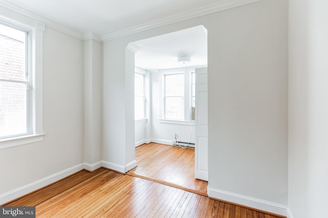 empty room with crown molding, a baseboard radiator, plenty of natural light, and light hardwood / wood-style floors