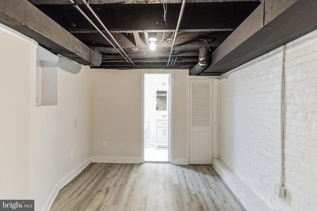 basement with brick wall and hardwood / wood-style floors