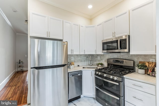 kitchen with crown molding, stainless steel appliances, sink, white cabinetry, and light hardwood / wood-style floors