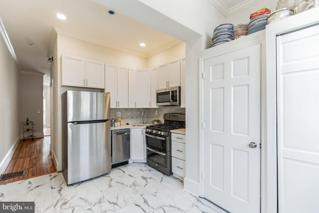 kitchen featuring tasteful backsplash, stainless steel appliances, light hardwood / wood-style floors, ornamental molding, and white cabinets