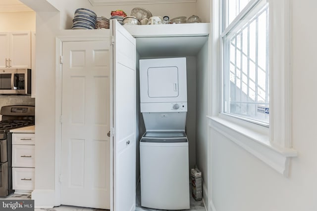 washroom featuring stacked washer / drying machine