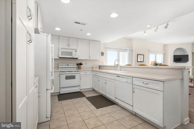 kitchen featuring white appliances, light tile patterned flooring, white cabinetry, sink, and kitchen peninsula