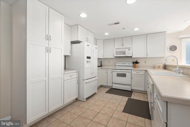 kitchen with light tile patterned floors, white appliances, sink, and white cabinetry