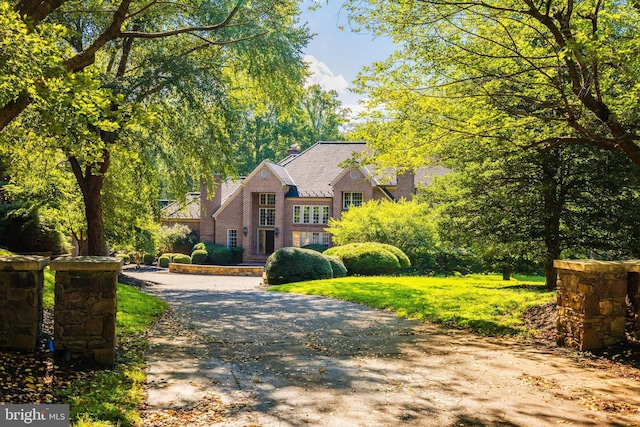 view of front of home with aphalt driveway, a chimney, and a front yard