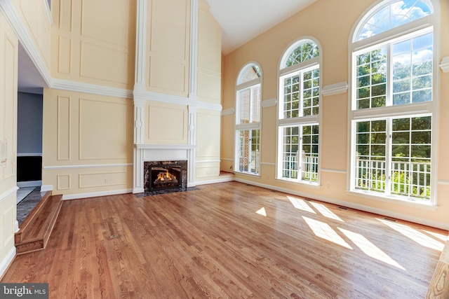 unfurnished living room featuring high vaulted ceiling, wood-type flooring, and a high end fireplace