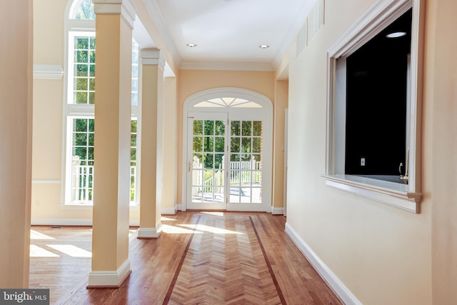 doorway featuring crown molding, hardwood / wood-style flooring, plenty of natural light, and decorative columns