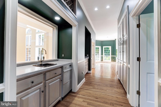 bar featuring light hardwood / wood-style flooring, a wealth of natural light, stainless steel dishwasher, and sink