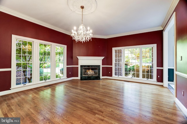 unfurnished living room with crown molding, a high end fireplace, hardwood / wood-style flooring, and a notable chandelier