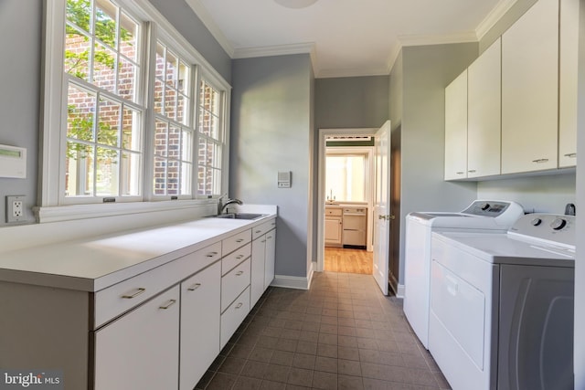 clothes washing area with washer and clothes dryer, crown molding, cabinets, and sink