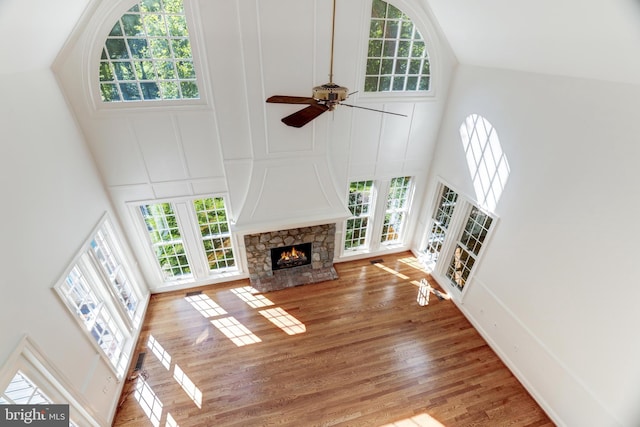 living room featuring high vaulted ceiling, ceiling fan, hardwood / wood-style flooring, and a fireplace