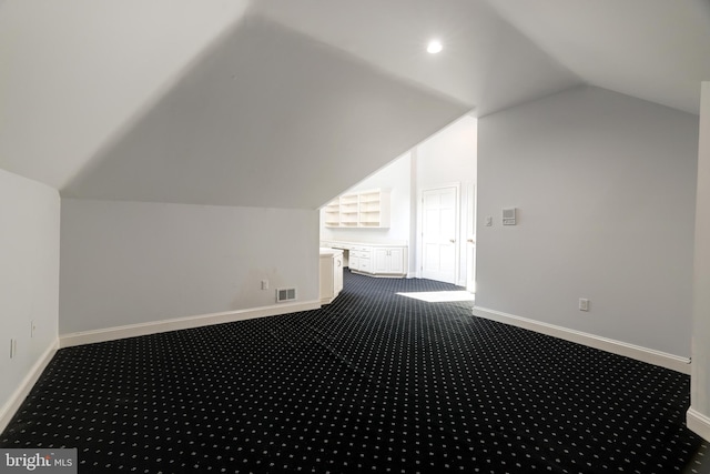 bonus room with vaulted ceiling and carpet