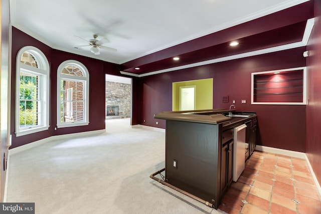 interior space featuring crown molding, light tile patterned floors, dishwasher, ceiling fan, and a stone fireplace