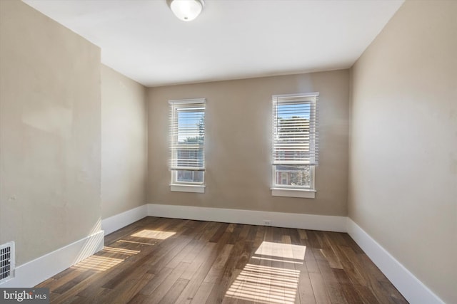 empty room featuring dark wood-type flooring and a wealth of natural light