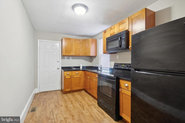 kitchen featuring black appliances, light hardwood / wood-style floors, and sink