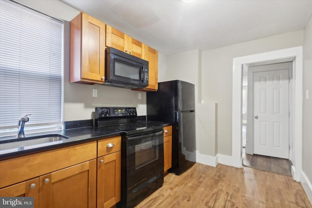 kitchen with black appliances, sink, and light hardwood / wood-style flooring