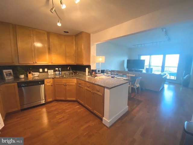 kitchen with dark hardwood / wood-style floors, sink, dark stone countertops, stainless steel dishwasher, and kitchen peninsula