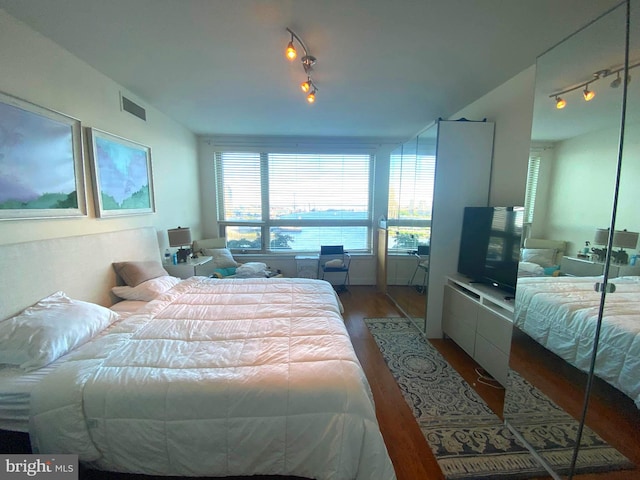 bedroom with hardwood / wood-style floors and rail lighting