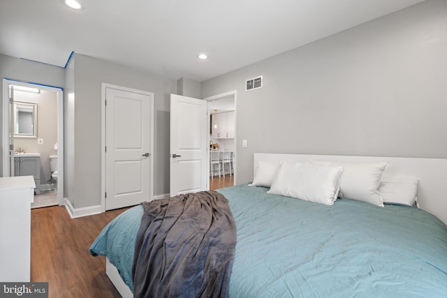 bedroom featuring dark hardwood / wood-style flooring and ensuite bath