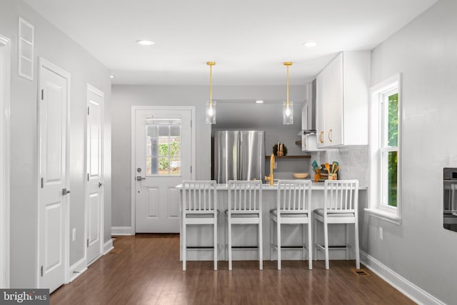 kitchen with a wealth of natural light, pendant lighting, and stainless steel fridge