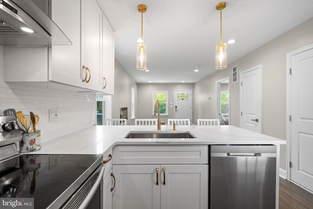 kitchen with stainless steel appliances, kitchen peninsula, sink, hanging light fixtures, and dark hardwood / wood-style floors