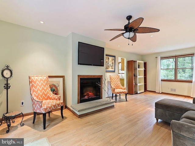 sitting room featuring baseboards, a ceiling fan, a glass covered fireplace, light wood-style flooring, and recessed lighting