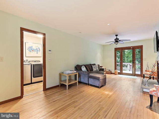 living area featuring a ceiling fan, washer and clothes dryer, light wood-style flooring, and baseboards