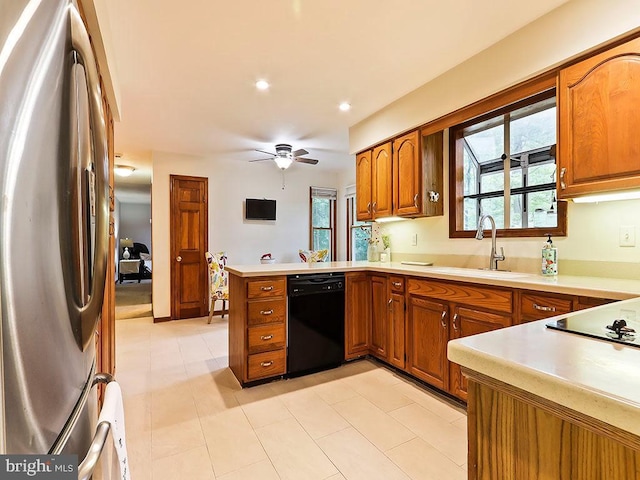 kitchen featuring dishwasher, light countertops, a sink, and freestanding refrigerator