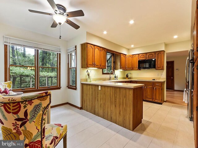 kitchen with black oven, stainless steel fridge, and light hardwood / wood-style flooring