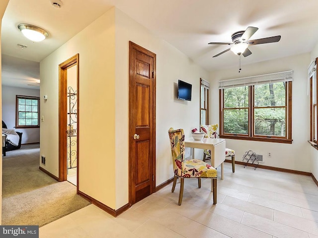 living area with light carpet, ceiling fan, and baseboards