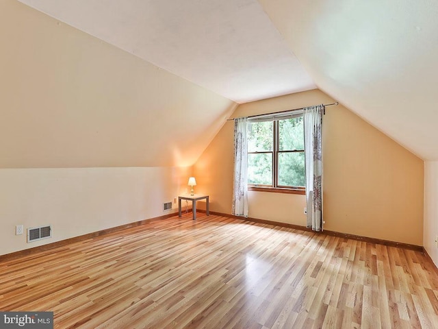 additional living space featuring lofted ceiling, light wood-style flooring, visible vents, and baseboards