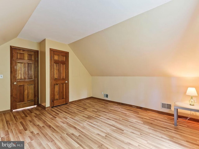 bonus room featuring baseboards, visible vents, vaulted ceiling, and light wood finished floors