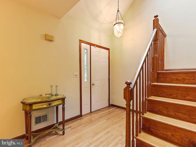 foyer entrance with stairs, visible vents, light wood-style flooring, and baseboards