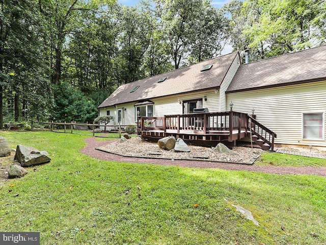 back of house with roof with shingles, fence, a deck, and a yard