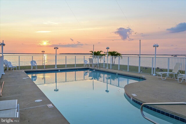 view of pool with a lawn and a water view